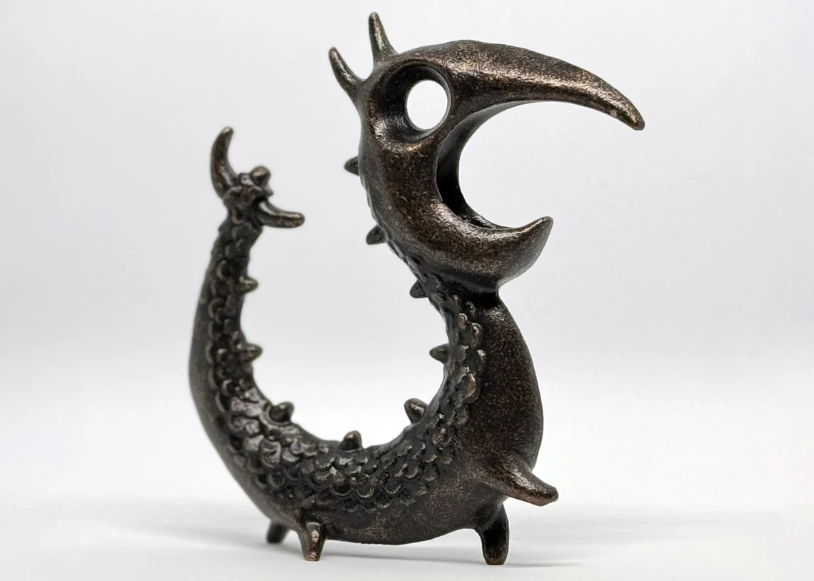 Sculptural metal Dragon Opener shown in profile on a neutral studio background.