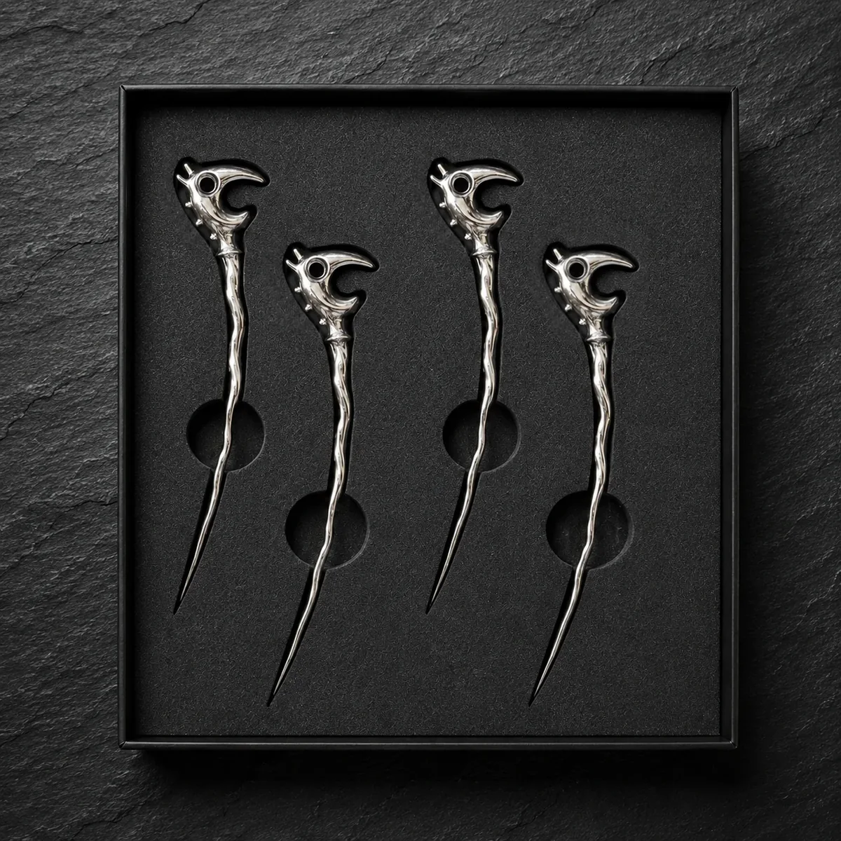Four chrome Dragon Picks centered in revised black foam openings inside the box.