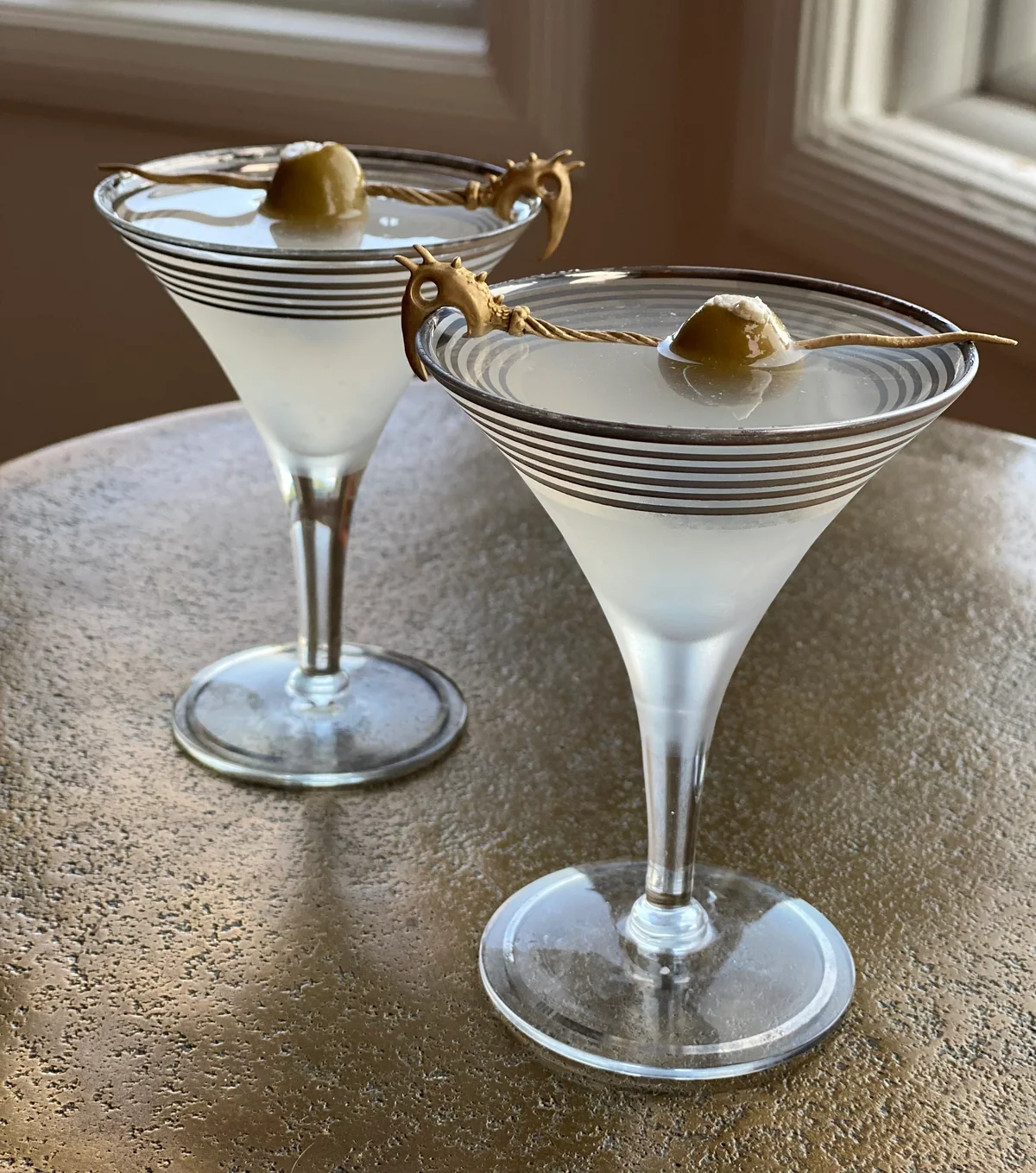 Early metal Dragon Picks resting across cocktail glasses.