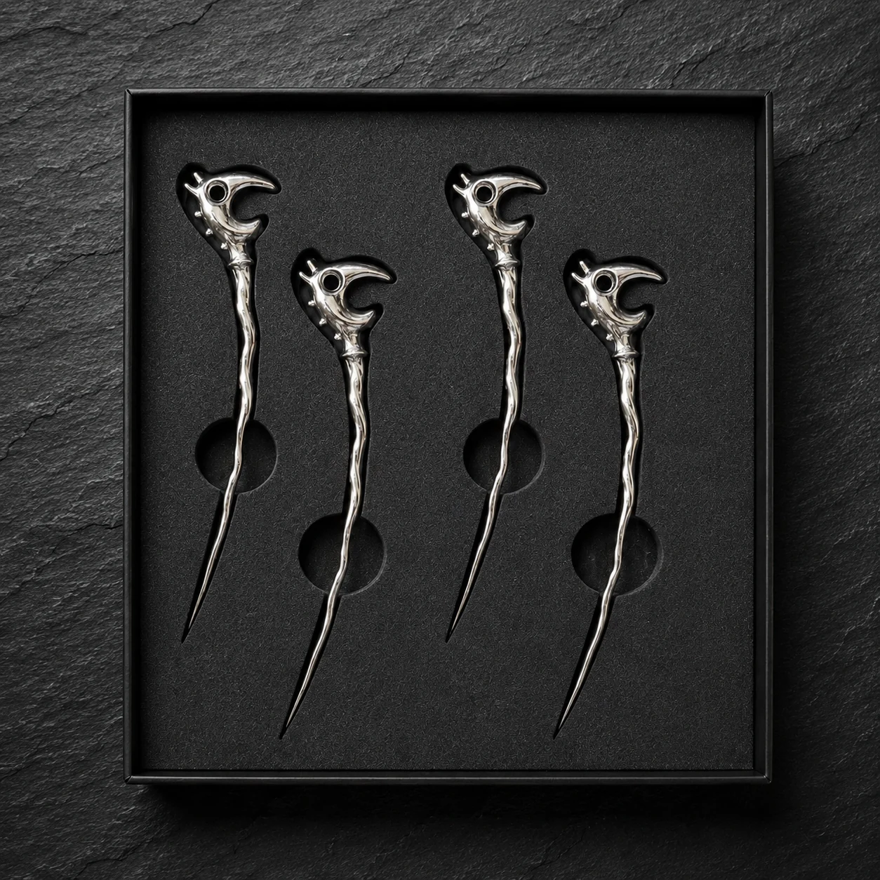 Four chrome Dragon Picks arranged in an open black presentation box.