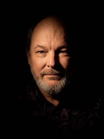 Dylan Sisson in a dramatically lit portrait against a black background.
