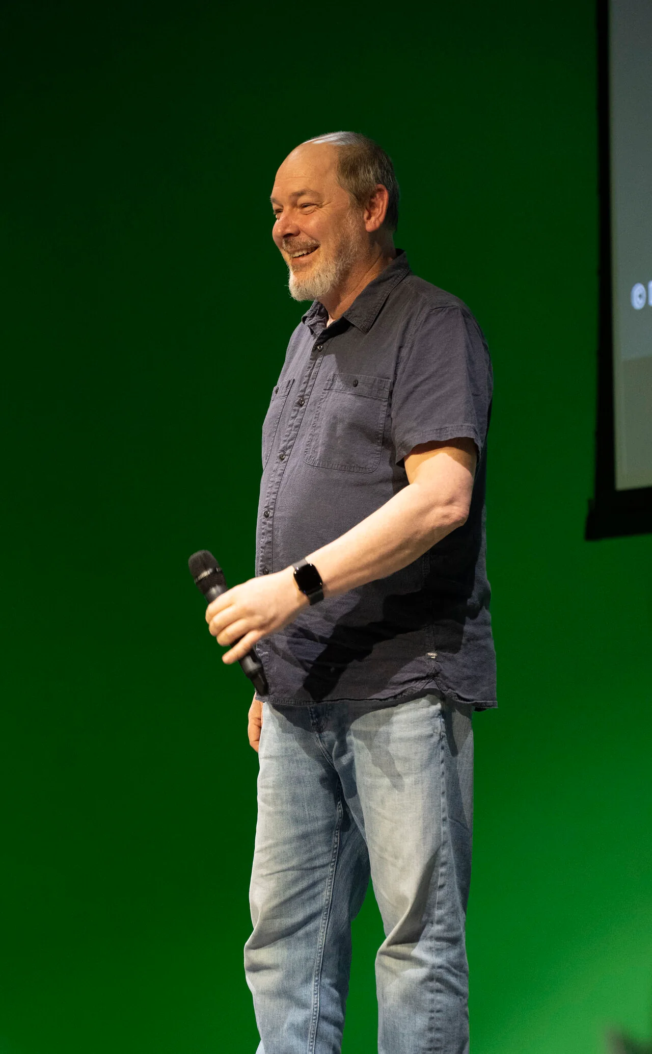 Dylan Sisson smiling onstage at Gnomon in Los Angeles, holding a microphone.