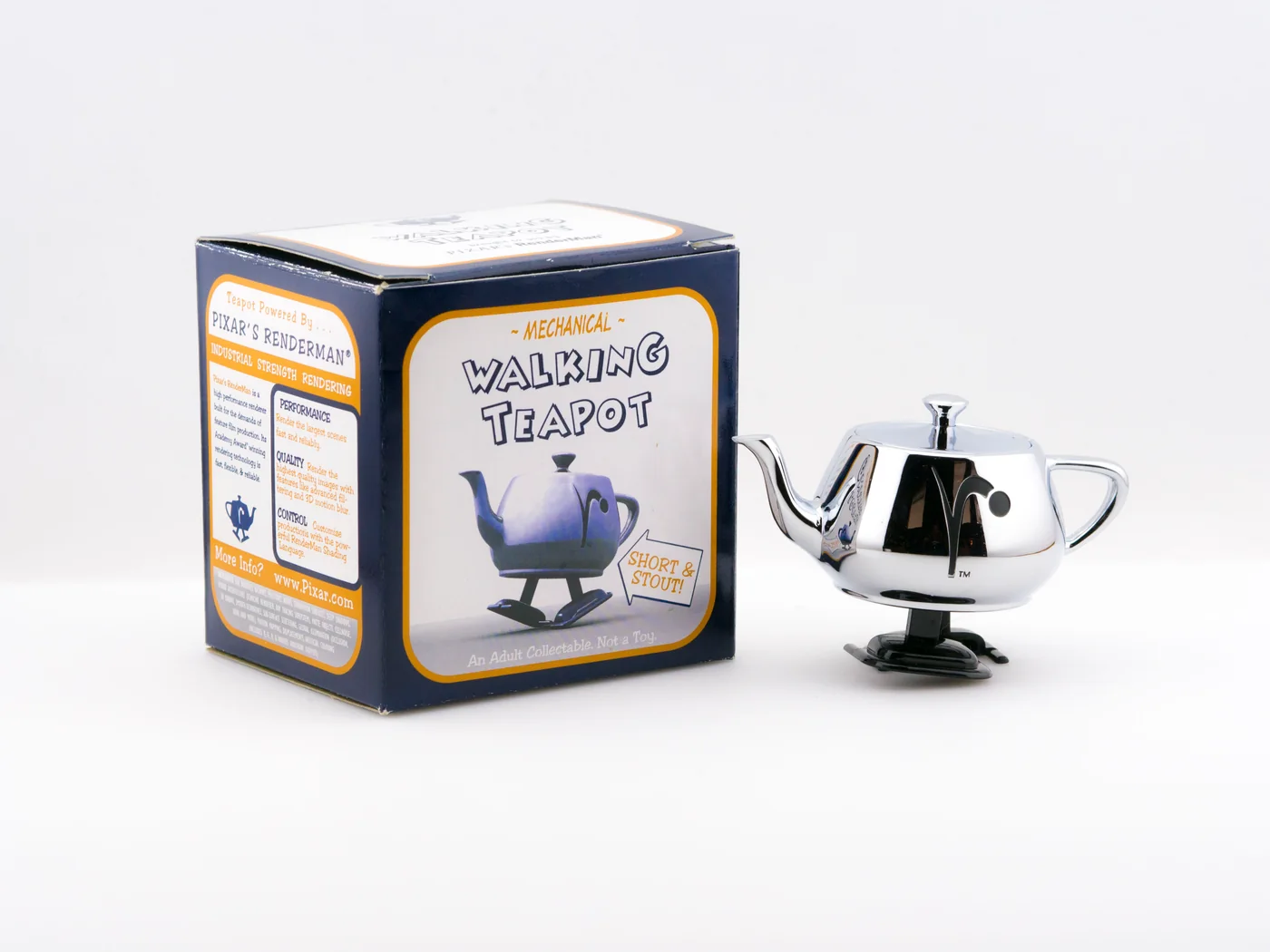 The original silver Walking Teapot beside its illustrated box on a pale studio background.
